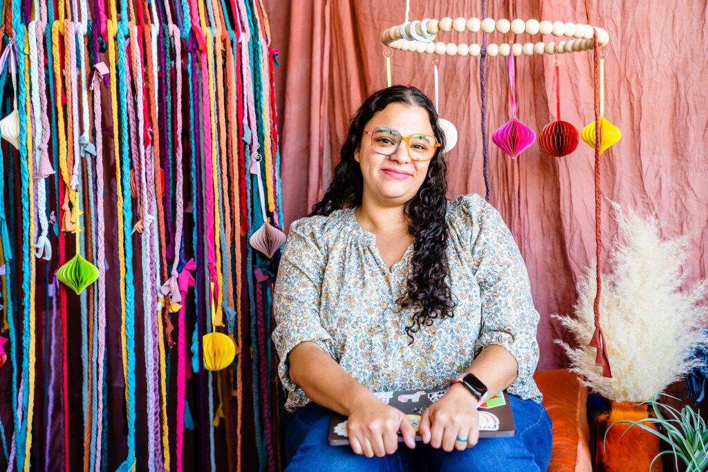 Colie James sits for photograph in front of colorful backdrop.