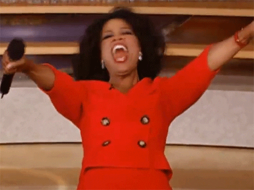 An excited woman in a red suit with her arms thrown wide, celebrating all the client videos Mori added after setting up Dubsado for designers.